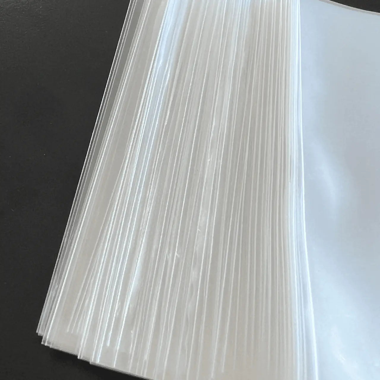 Stack of white paper sheets highlighting page edges beside Max Pro Card Sleeves for Trading Cards