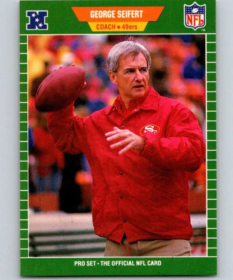 Football coach in red 49ers jacket holding football, representing George Seifert football card