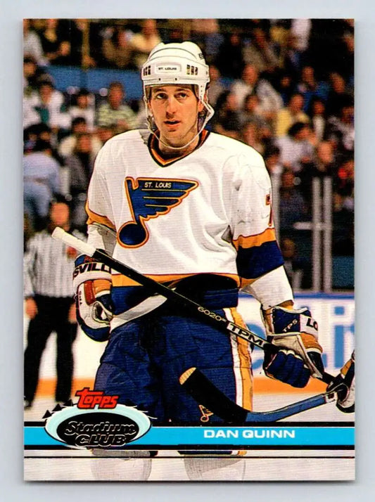 Hockey player in a white St. Louis Blues jersey on ice with Dan Quinn hockey card