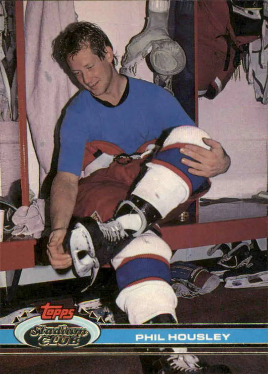 Phil Housley in blue shirt adjusting gear in Winnipeg Jets locker room hockey card image