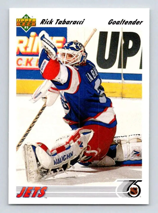 Hockey goalie Rick Tabaracci in blue and red uniform making a save for Winnipeg Jets