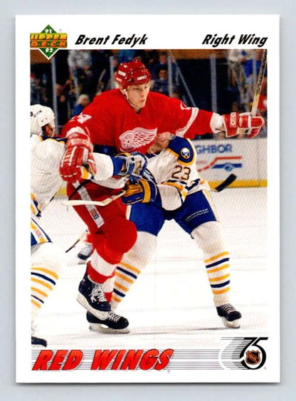 Hockey player in Detroit Red Wings jersey competes against opponent in blue and yellow uniform