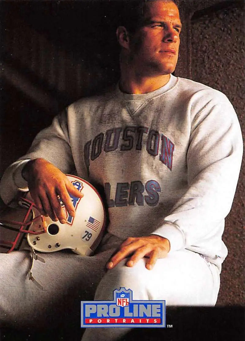 Player in Houston Oilers sweatshirt holding helmet next to Ray Childress football card