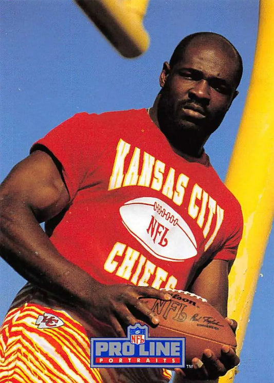 Christian Okoye in red sleeveless shirt holding football for Pro Line Portraits Kansas City Chiefs