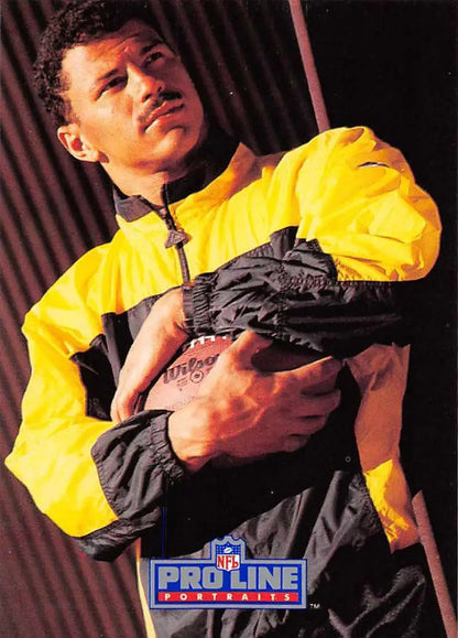 Person in a yellow jacket with black sports apparel holds a Rod Woodson Football Card