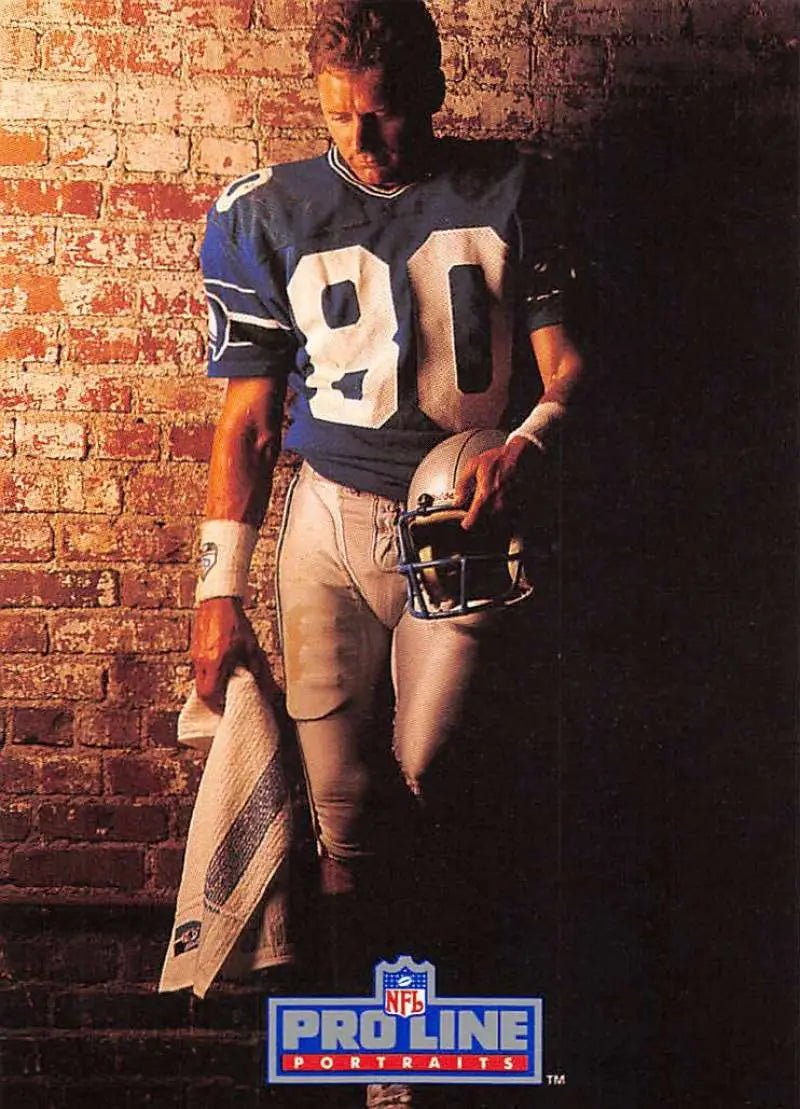 Steve Largent in blue #90 jersey holding helmet against brick wall for Pro Line Portraits