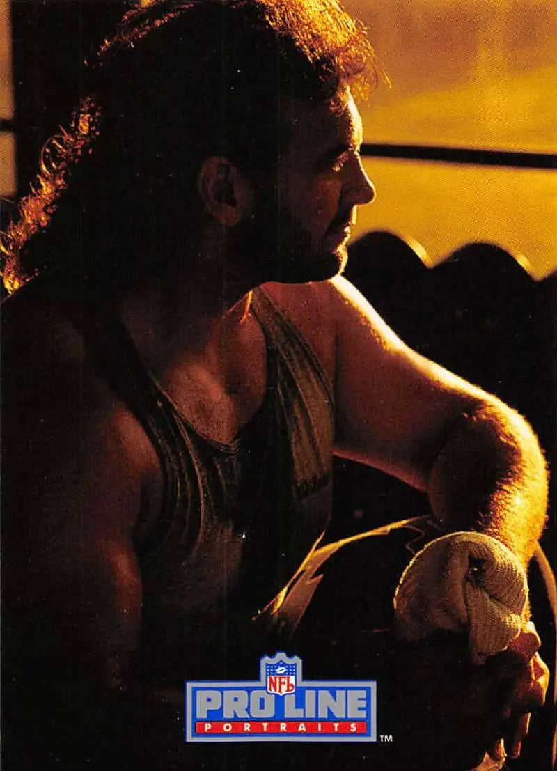 Muscular side profile of Bob Golic in tank top, highlighted by golden lighting