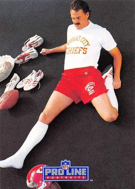 Person in Kansas City Chiefs gear beside football shoes and a Nick Lowery card