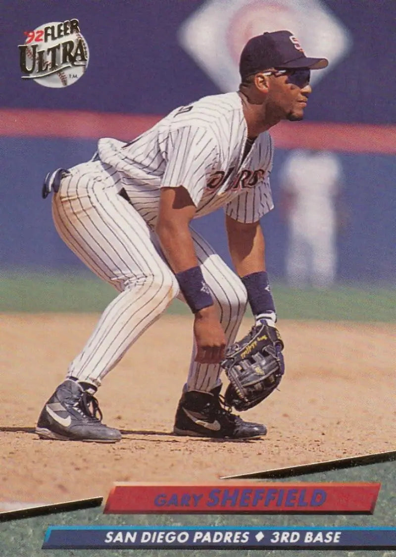 Baseball player in San Diego Padres pinstriped uniform crouched in fielding stance