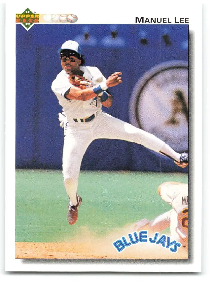 Baseball player in Toronto Blue Jays uniform leaping to make a throw in action