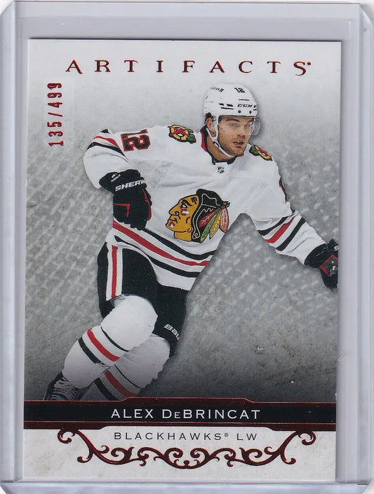 Hockey trading card of Alex DeBrincat Chicago Blackhawks in white jersey 135/499 Upper Deck Artifacts