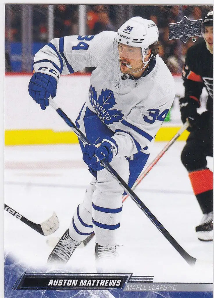 Hockey player in a white Toronto Maple Leafs jersey skating with a stick, Auston Matthews