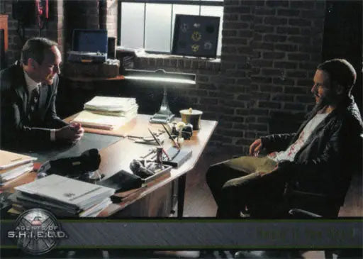 Two people discussing Marvel Agents of SHIELD trading cards at an office desk