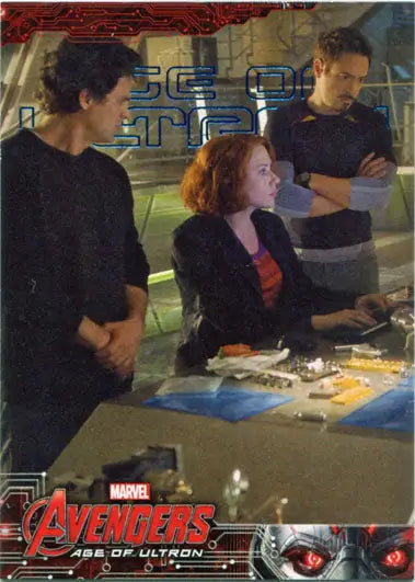 Three people in a high-tech setting examining a Marvel Avengers trading cards display