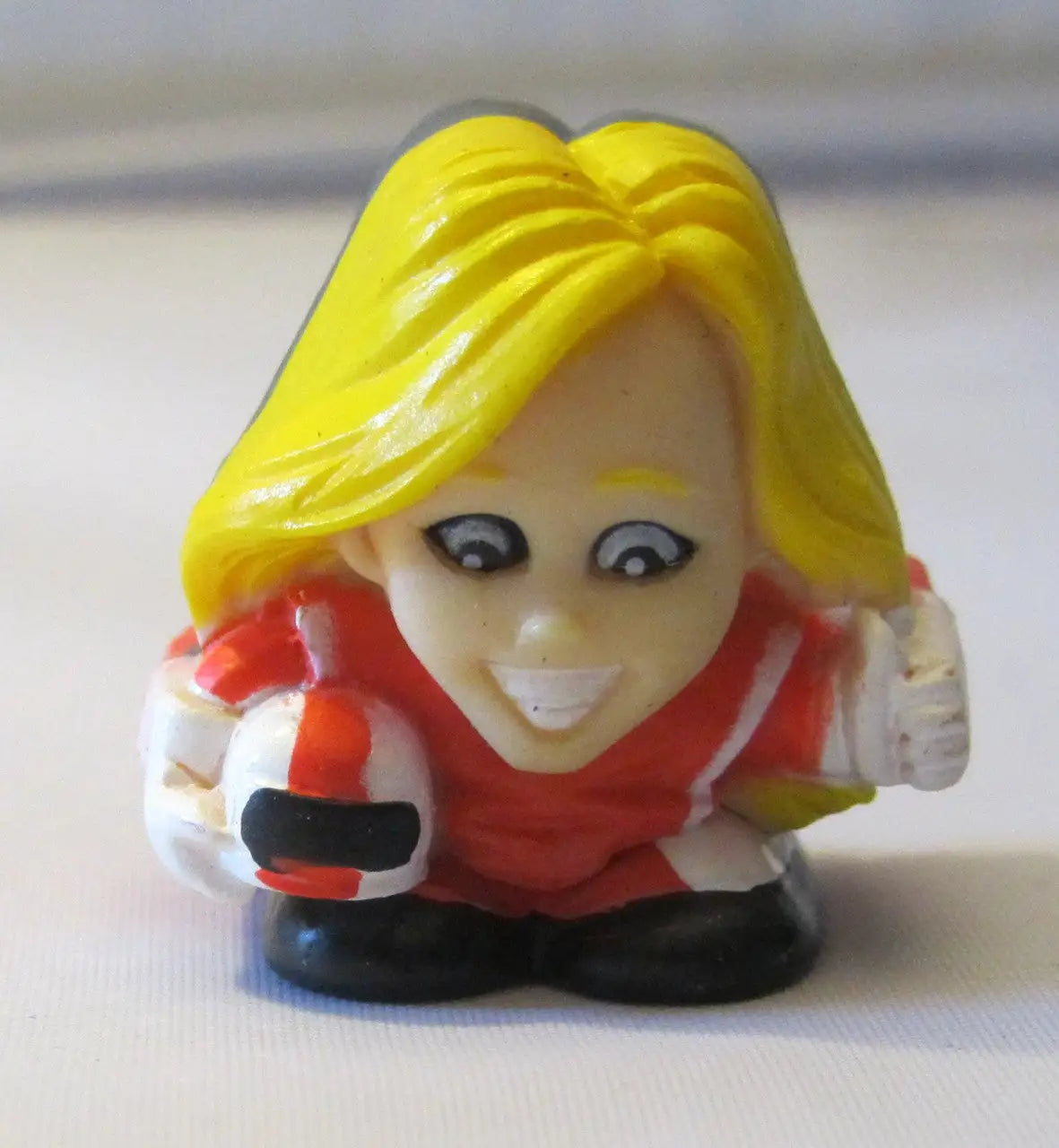 Small plastic figurine of a smiling character from NFL TeenyFreaks series with bright yellow hair