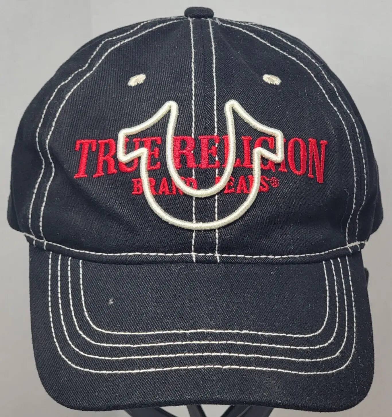 Navy blue True Religion baseball cap with red text and white horseshoe logo