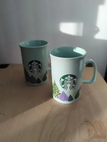 Two light blue Starbucks coffee mugs from the holiday Christmas collection set