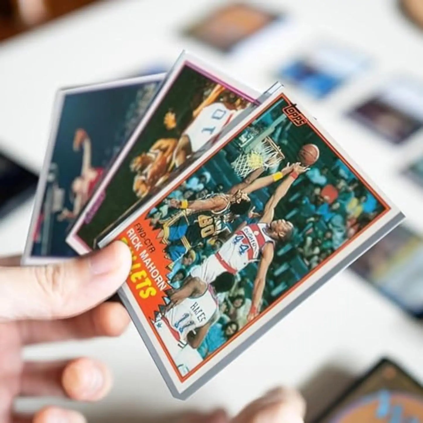 Hand holding vintage basketball trading cards with premium card protection sleeves